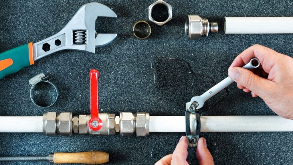 Plumber repairing a pipe valve with an adjustable wrench in Spring Hill