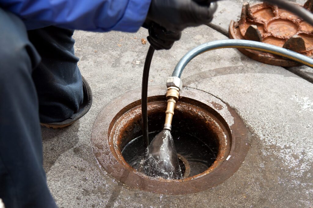 Plumber hydro jetting a sewer line through a manhole in Spring Hill