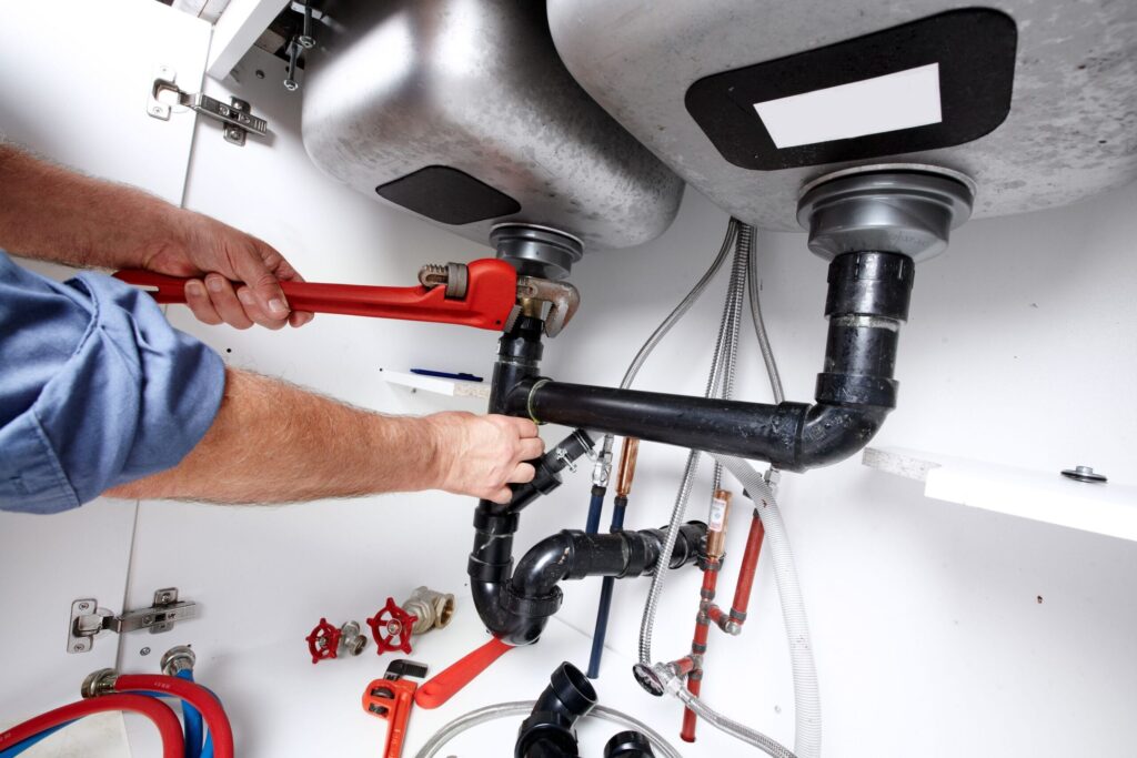 Plumber repairing drain pipes beneath a kitchen sink in Spring Hill