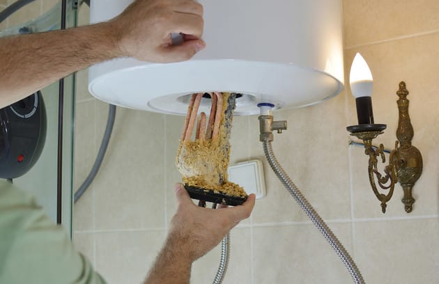 Technician removing mineral buildup from a water heater in Spring Hill